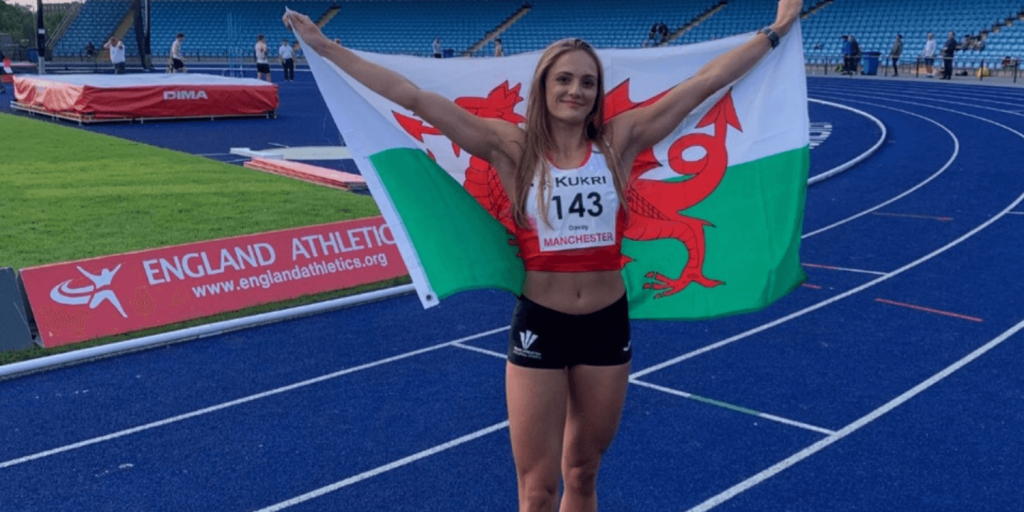 Welsh heptathlete holding up the Wales flag in celebration