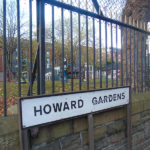A picture of the Howard Gardens green space sign with the park in the background