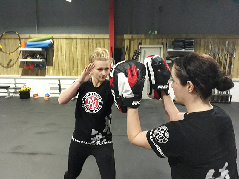 One women is wearing pads preparing for the other woman to punch them