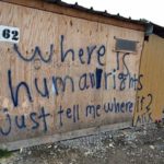 A shelter in a Calais refugee camp showing the words: where is humanity just tell me where?