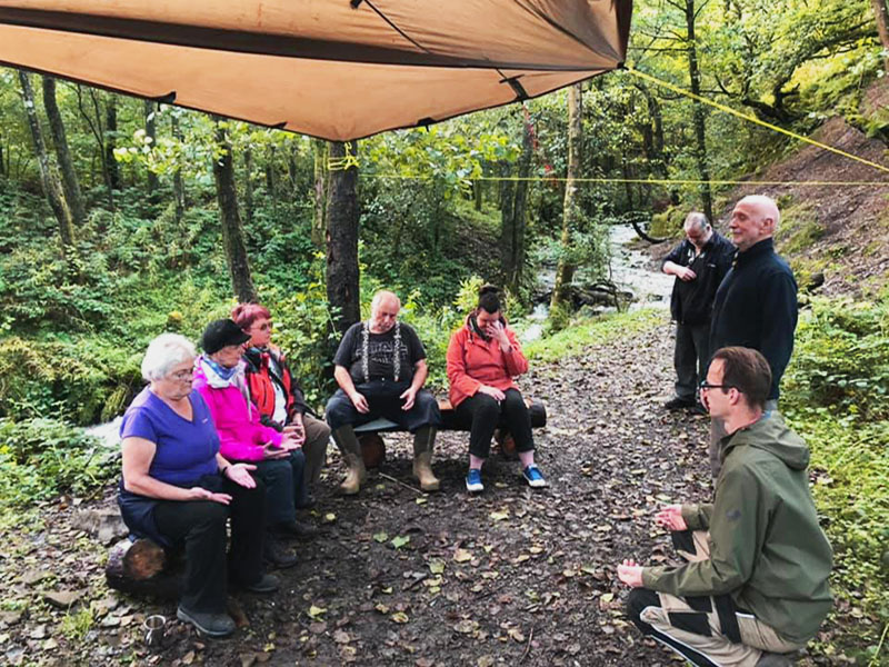 A group of people attending woodland therapy wellbeing sessions in the woods