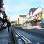 Treorchy high Street on a Saturday, showing shoppers and shop fronts, and flags and bunting