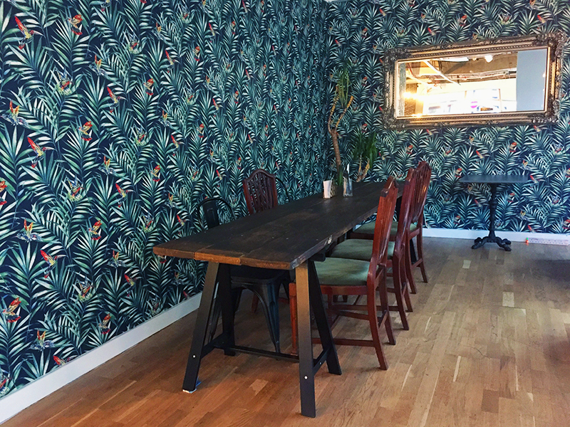 long wooden table with chairs in room with green wallpaper and mirror