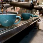 Row of blue coffee cups under espresso machine