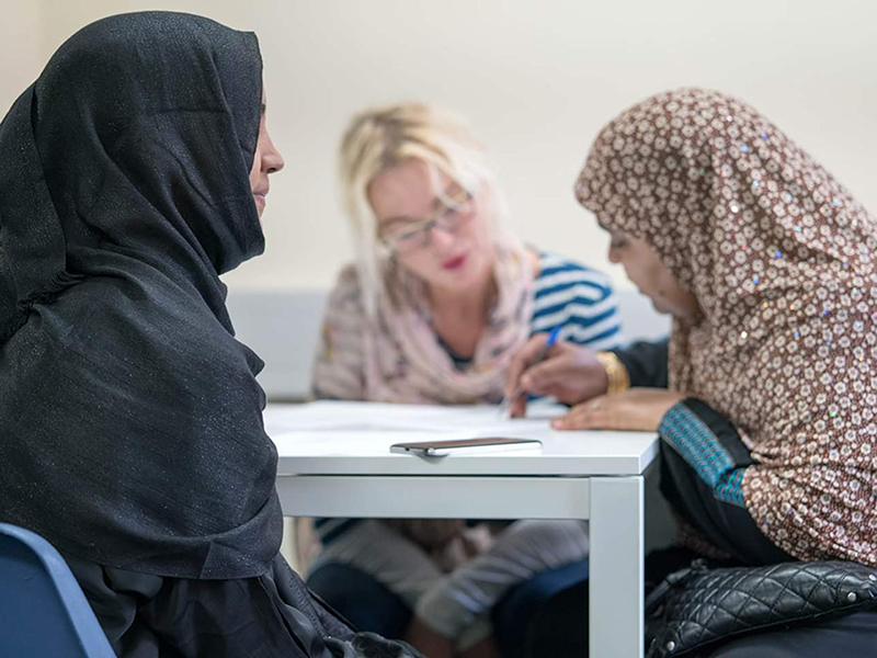 A photo of two asylum seekers in a classroom in Cardiff learning English