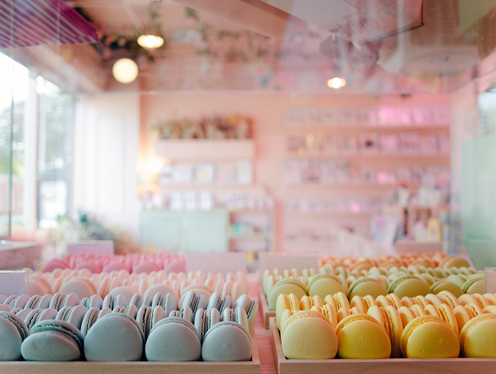 Pastel coloured macarons with the shop in the background 