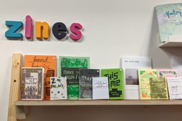 colourful sign reading "zine" and zines on shelf