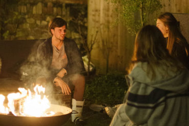 Young people sitting around a fire outdoors