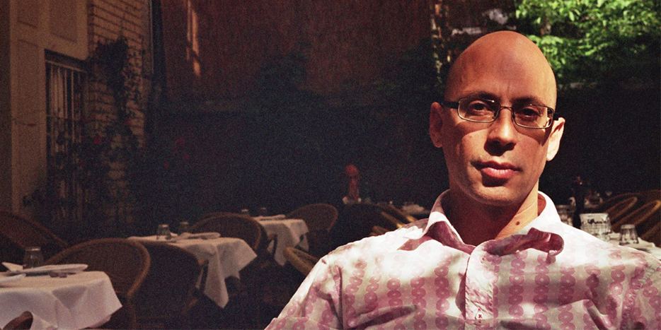 Image of a bald man sitting at a table on holiday