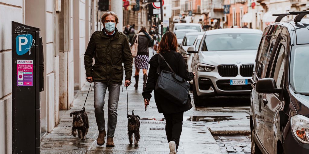 Man walking his dog down a street, with a covid-19 safe mask