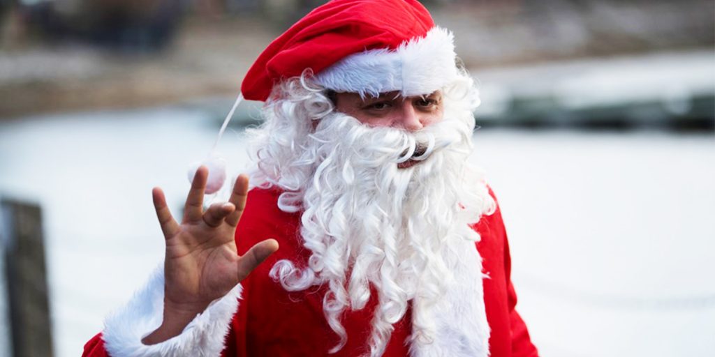 A man dressed as Santa waves at the camera as he participates in the Santa Dash in Cardiff