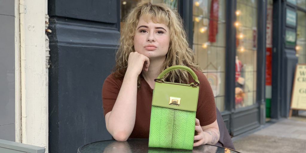 Woman sitting with her hand on a green handbag.