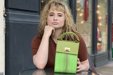 Woman sitting with her hand on a green handbag