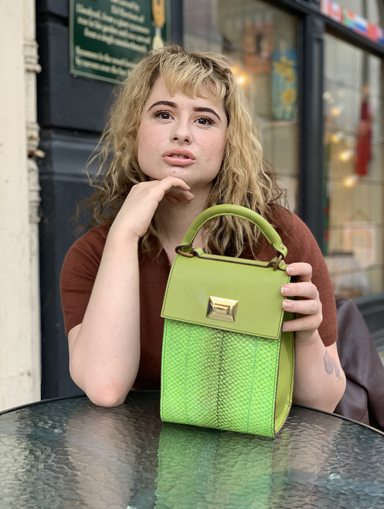 Woman sitting and posing with a green handbag
