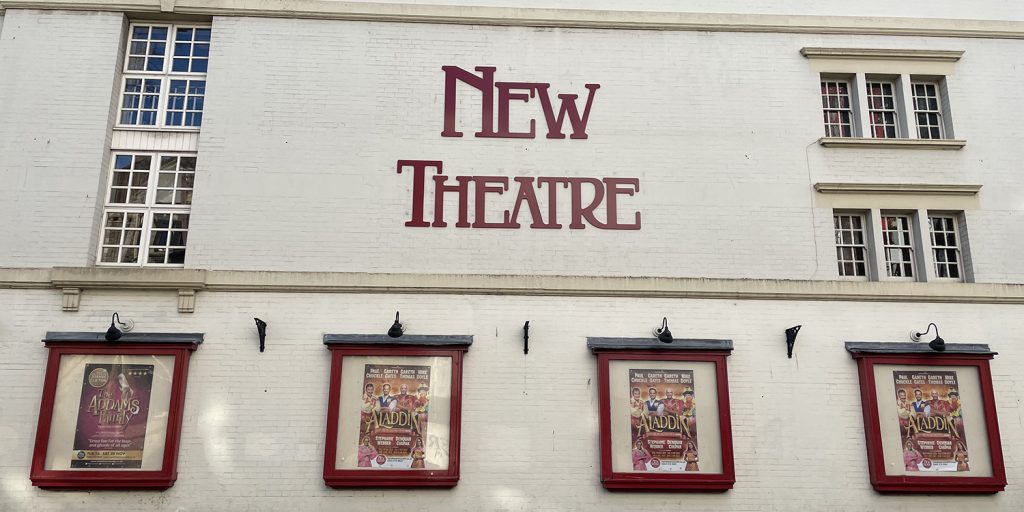The New Theatre in Cardiff with posters of The Addams Family and Aladdin productions in frames on the wall