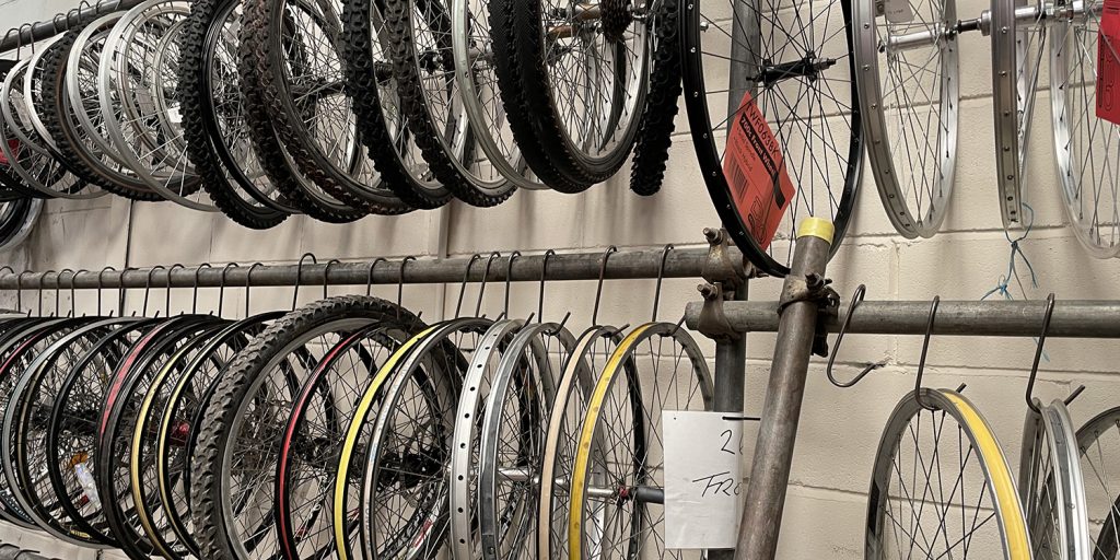 Bike wheels, tyres and wheel frames hanging up along a wall.