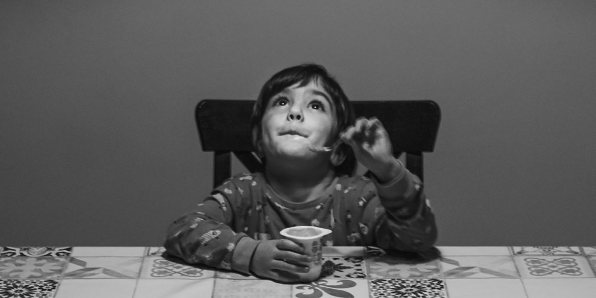 Young boy eating a yoghurt and looking up