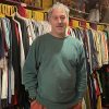 The picture shows a vintage clothing shop owner in his store