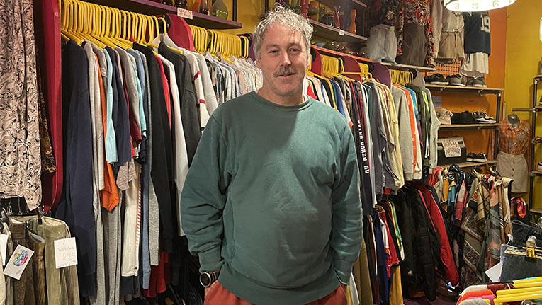 Shop owner of vintage thrift store poses in his shop