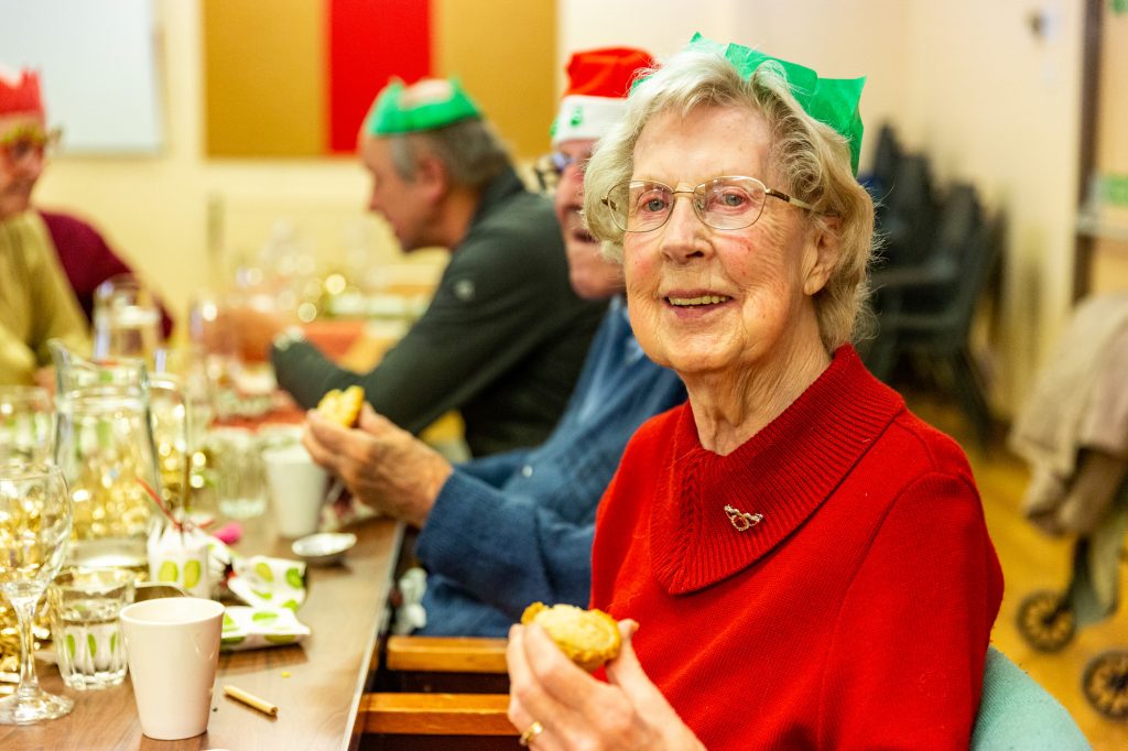 An old lady celebrates Christmas with her community. 