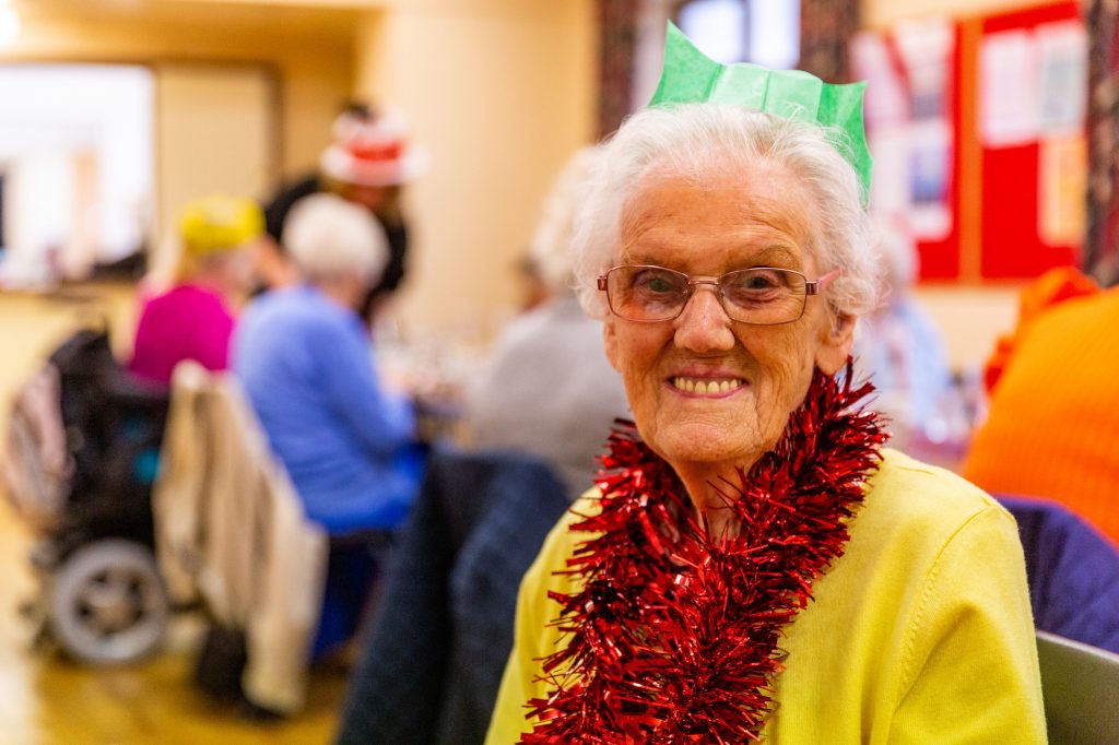 An old lady celebrates Christmas with her community. 