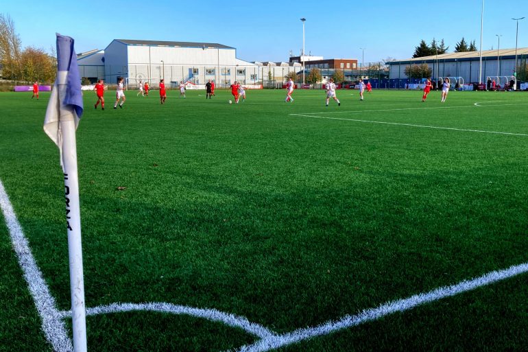 A football pitch with female football players visible in the background