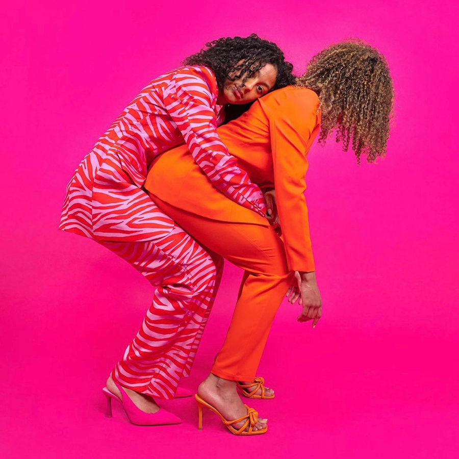 Two women dressed in pink and red suits representing the Cardiff creative community.