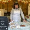 Karen Shellac stands in her Christmas stall with a chalkboard sign that states "Please note we only take cash payments"