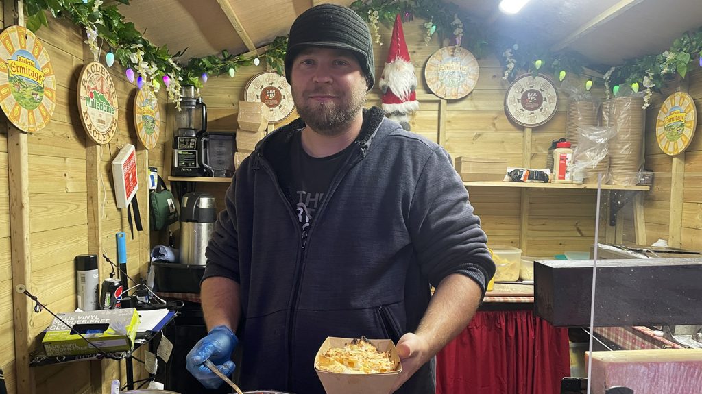 Simon Matthews stands in his Christmas stall with a nachos dish in hand.