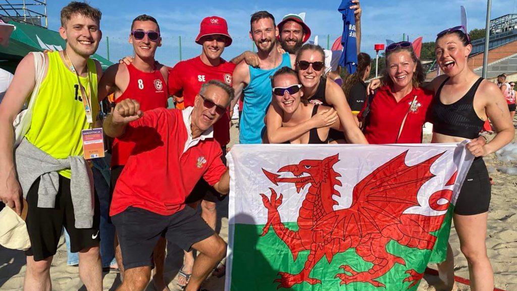 The Welsh beach korfball team and supporters holding the Welsh flag at the Beach Korfball World Cup in Poland, 2023.