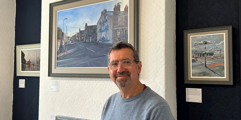 Cardiff artist Malcolm Murphy stands in Cathays Gallery, with his fine art paintings behind him