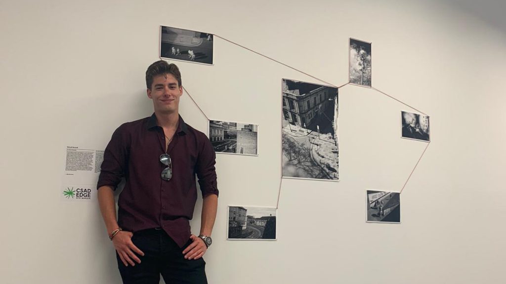 Photographer standing with his photos at graduate exhibition