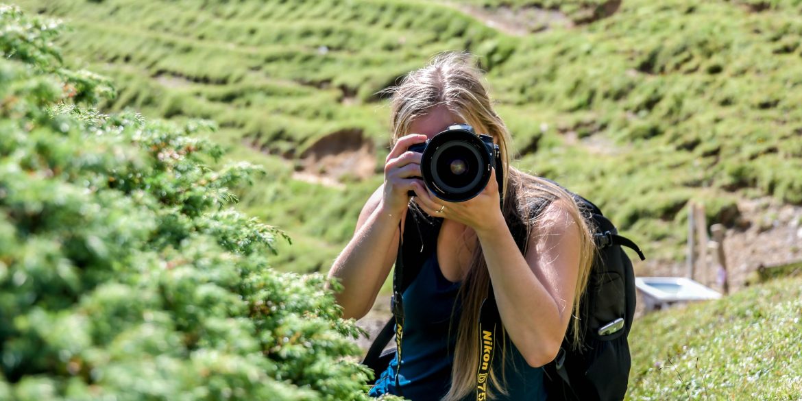 woman holding a camera and taking photos outdoors