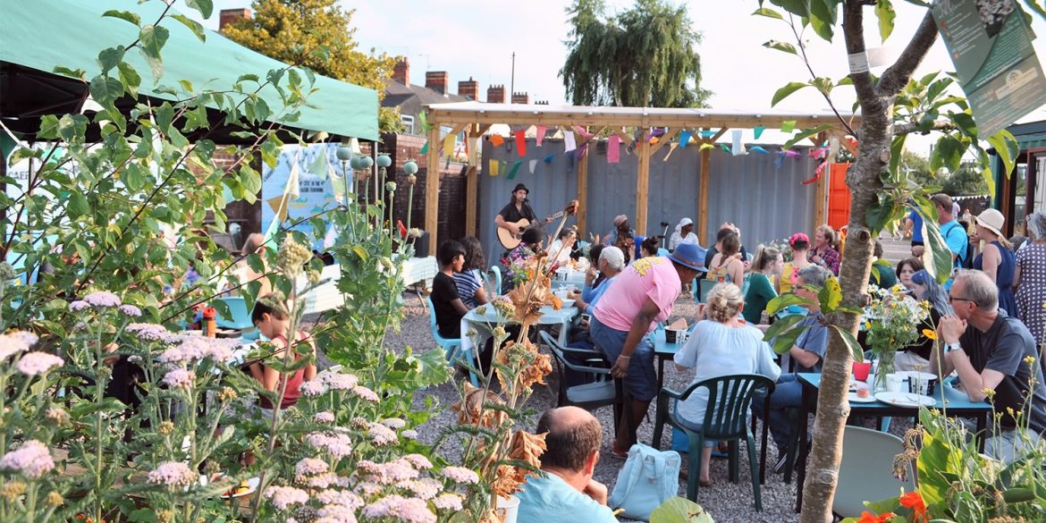 A group of people sat listening to an event in a public gardens