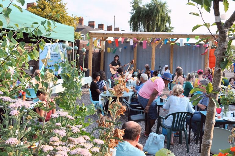 A group of people at an event in a public gardens which hosts live music and workshops about energy bills