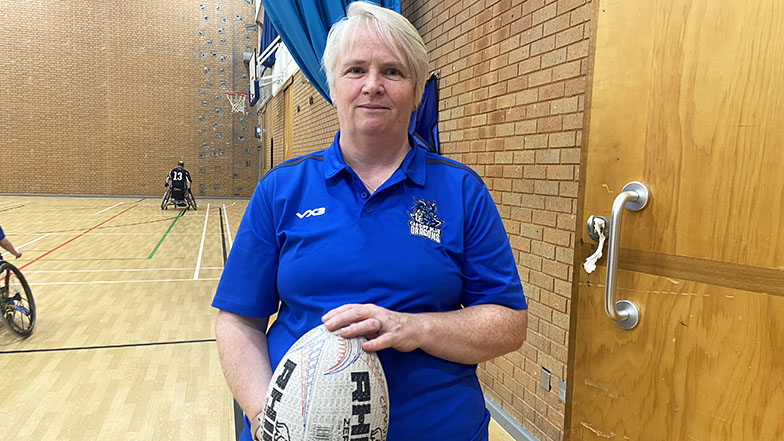 Photograph of the team manager holding one of the rugby balls used at training
