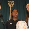 Three girls playing netball, laughing and smiling