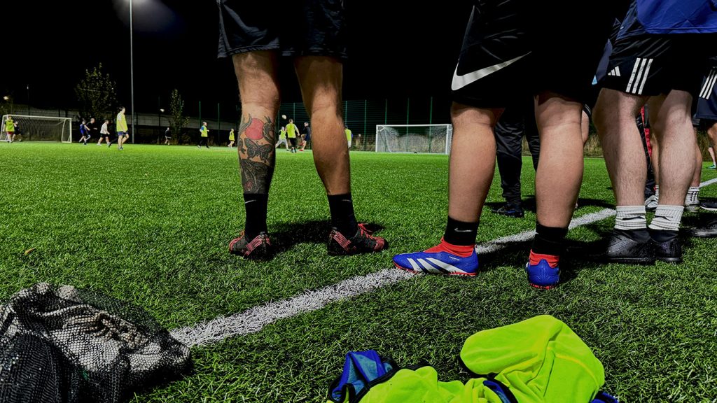 A group of football players stood on a pitch facing away from the camera.