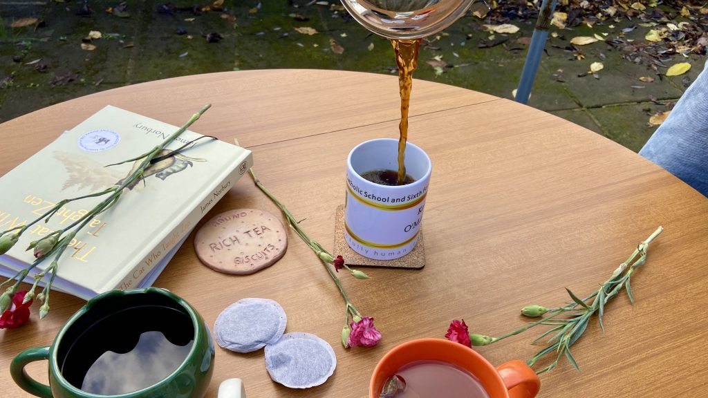 A coffee is being poured into a mug, surrounded by tea bags 