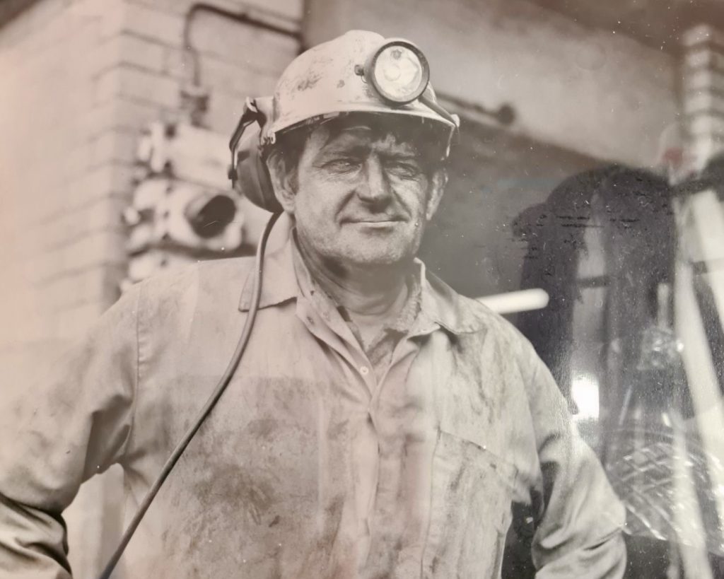 A miner looks at the camera in his work uniform 