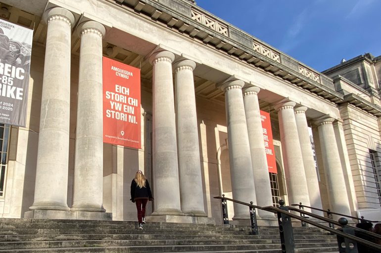 A visitor enters National Museum Cardiff on a sunny day