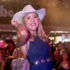 Women in cowboy hat at country music event.