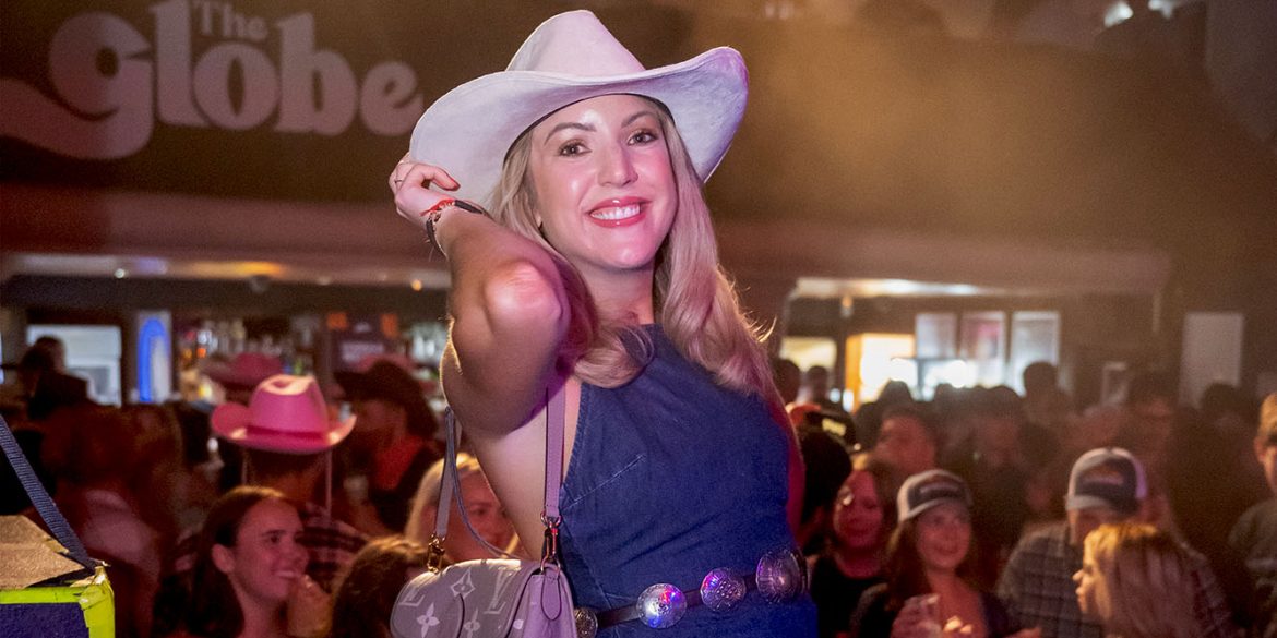 Women in cowboy hat at country music event.