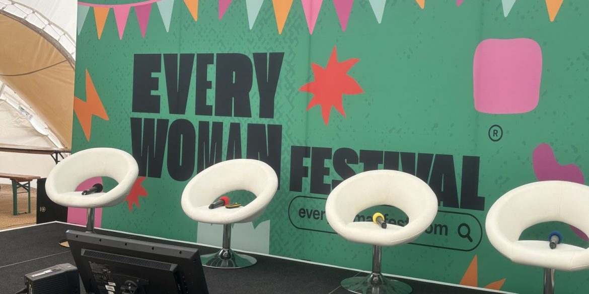 Everywoman festival background and a set of four chairs with microphones lying on them