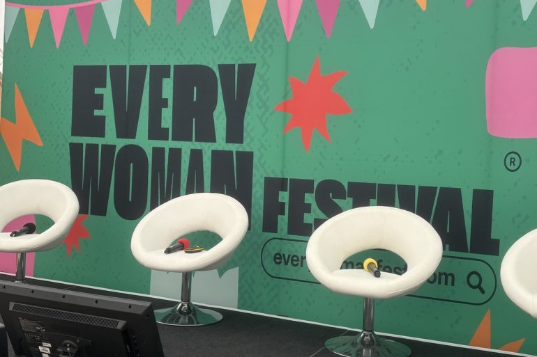 Everywoman festival background and a set of four chairs with microphones lying on them