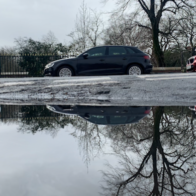 cars and sky reflected in a puddle