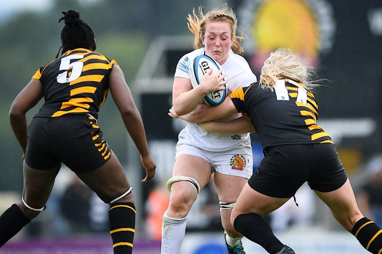 Welsh rugby player Abbie Fleming holds a rugby ball as she is tackled