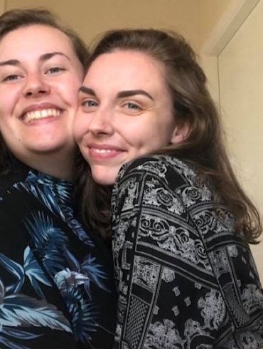 Two people embrace as they smile at the camera