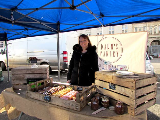 Image of a woman behind a cake stall 