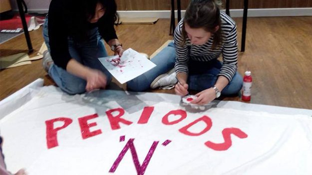 Volunteers work on a Periods in Poverty Banner.